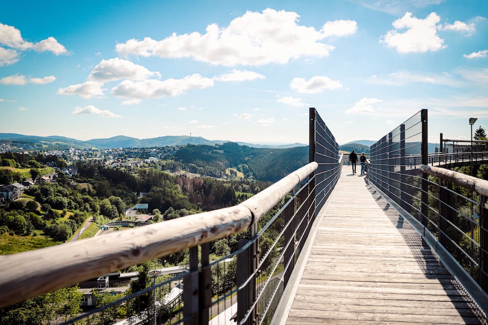 De indrukwekkende Panorama Erlebnis Brücke bij Winterberg, met een weids uitzicht over de groene heuvels van het Sauerland, wandelen in het Sauerland.